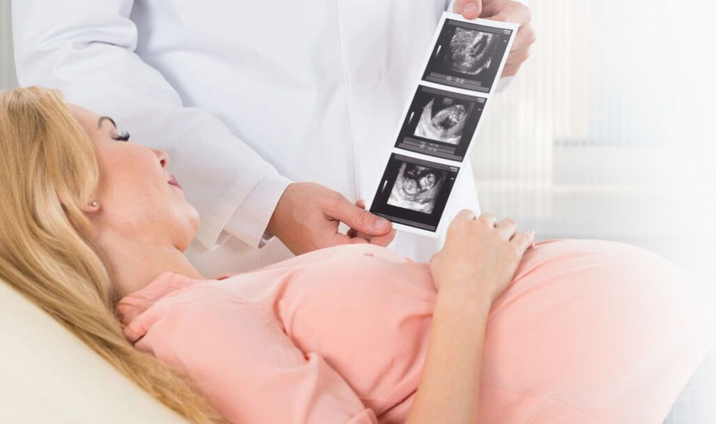 A doctor showing a pregnant woman ultrasound images.